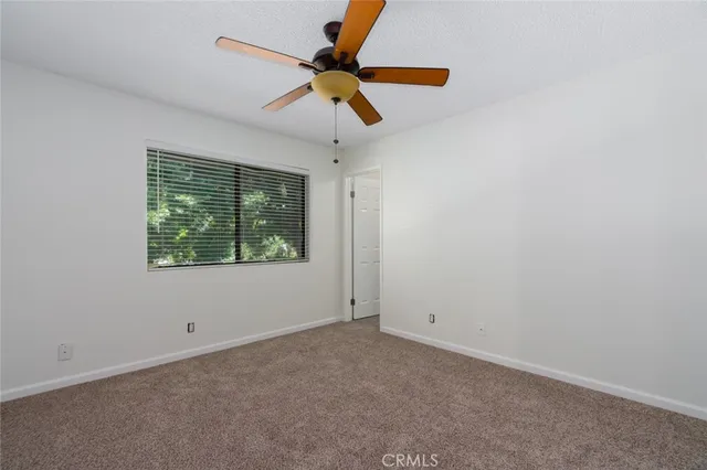 an empty room with ceiling fan and window
