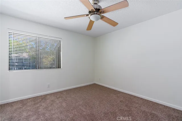 an empty room with a window and a fan
