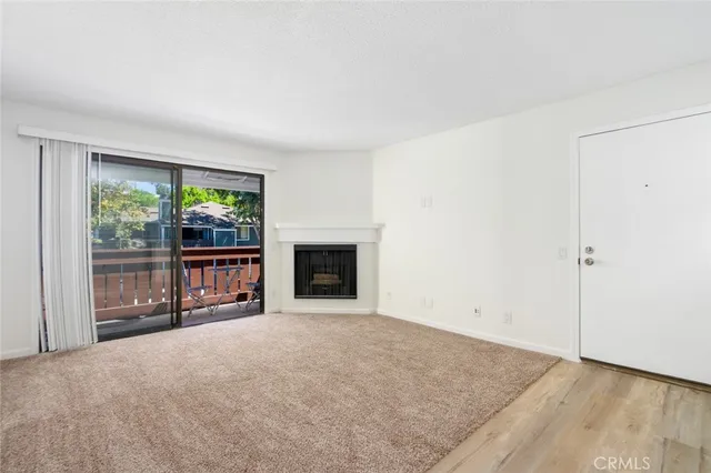 a view of an empty room with a fireplace and a window