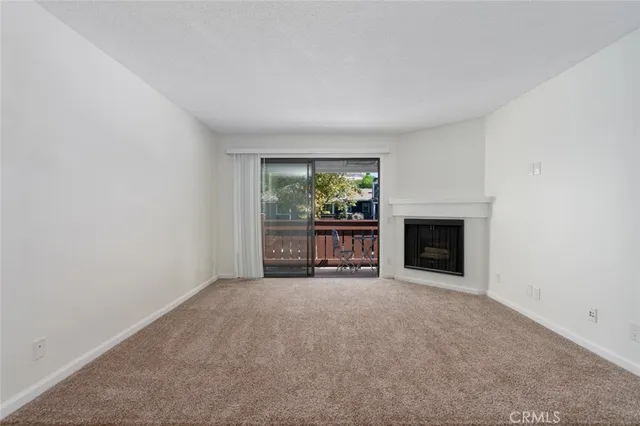 a view of an empty room with a fireplace and a window