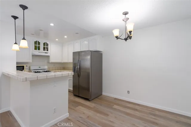 a kitchen with stainless steel appliances granite countertop a refrigerator a sink and white cabinets