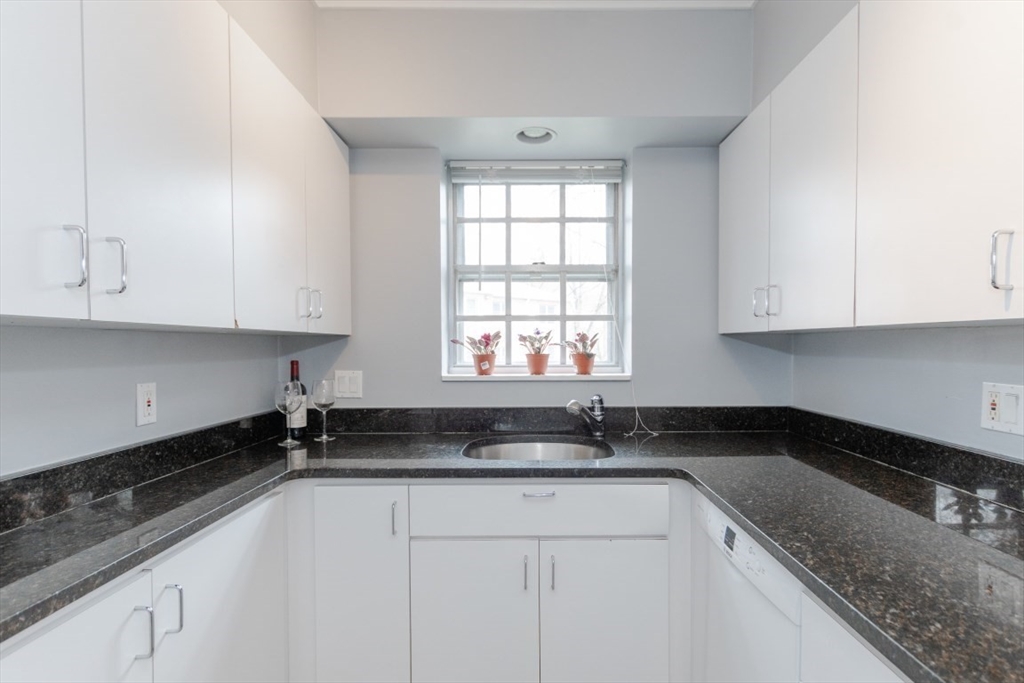 121 Lake Shore Road, Unit 2 Boston, MA 02135 - Photo 12 of 32 a kitchen with granite countertop white cabinets sink and window