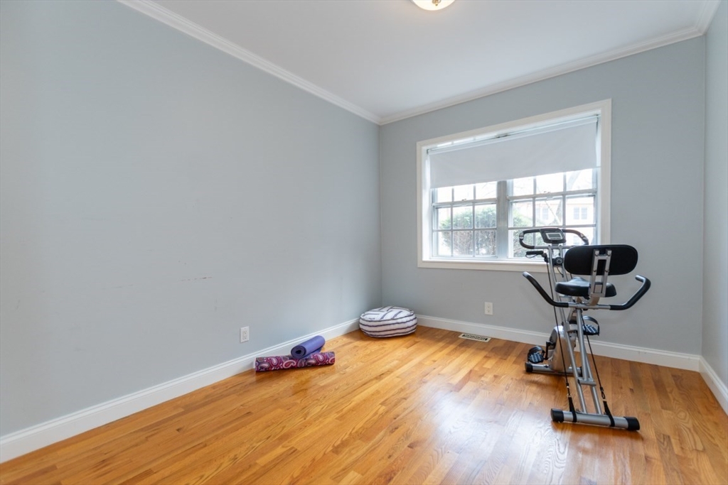 121 Lake Shore Road, Unit 2 Boston, MA 02135 - Photo 17 of 32 a room with gym equipment on wooden floor and windows