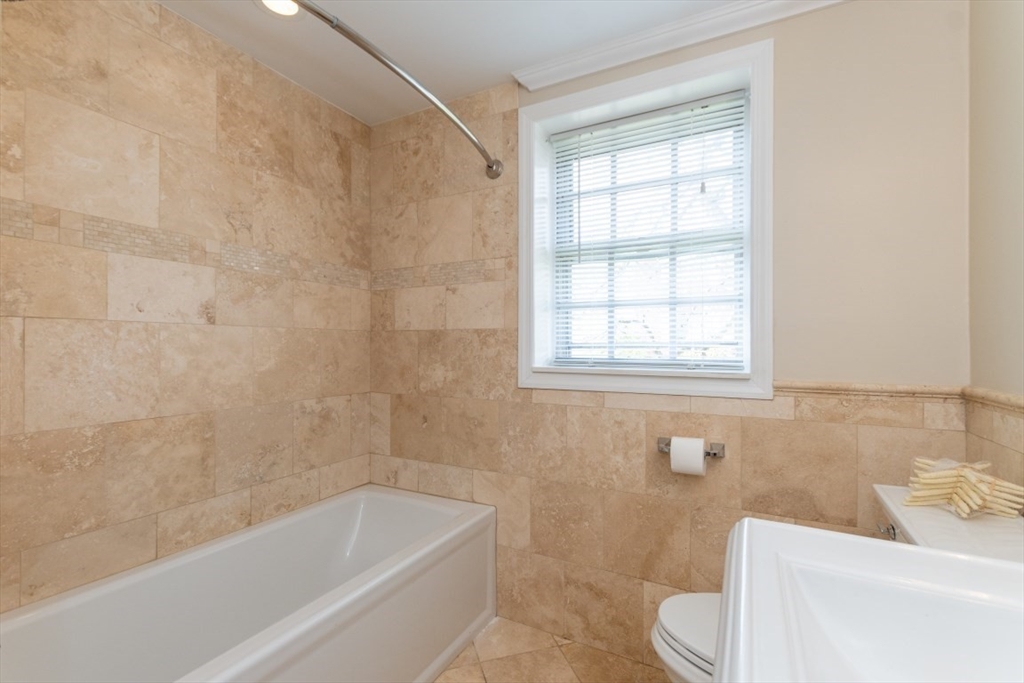 121 Lake Shore Road, Unit 2 Boston, MA 02135 - Photo 22 of 32 a bath tub sitting next to a white toilet and a window