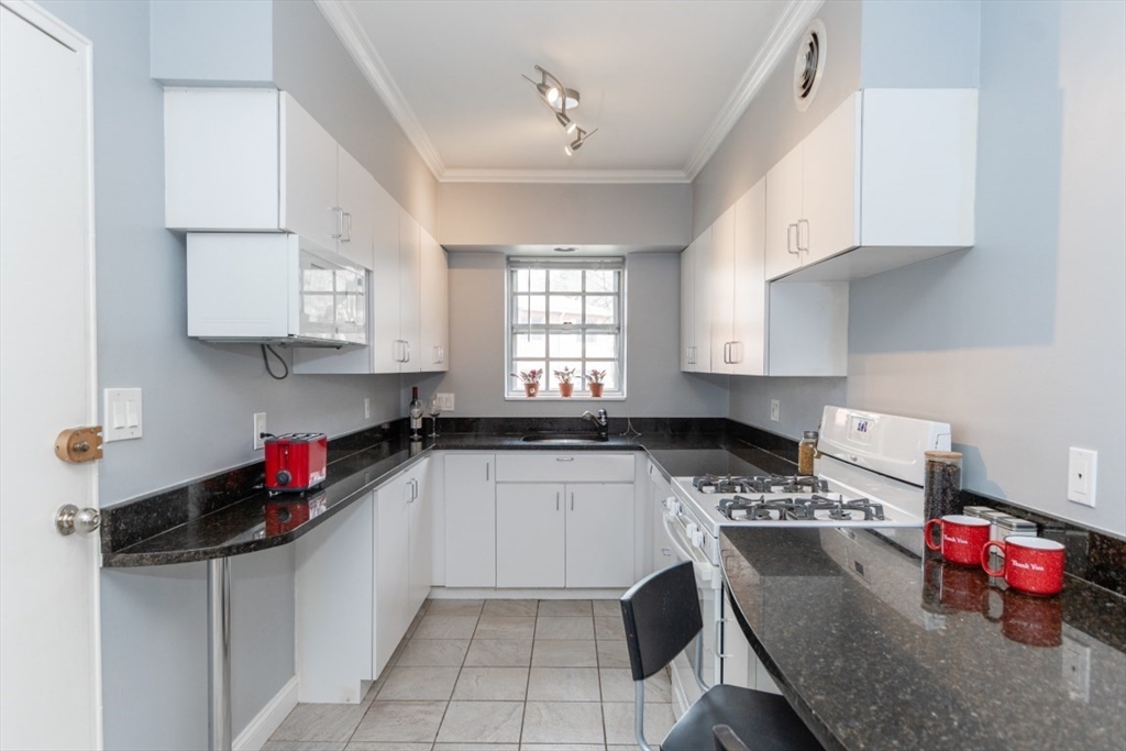 121 Lake Shore Road, Unit 2 Boston, MA 02135 - Photo 9 of 32 a kitchen with granite countertop a sink dishwasher a stove and cabinets