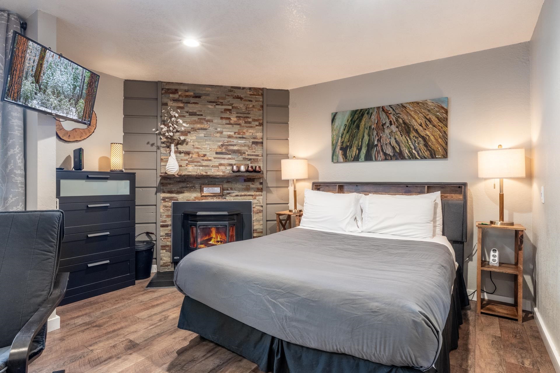 Bedroom with wood finished floors and a stone fireplace
