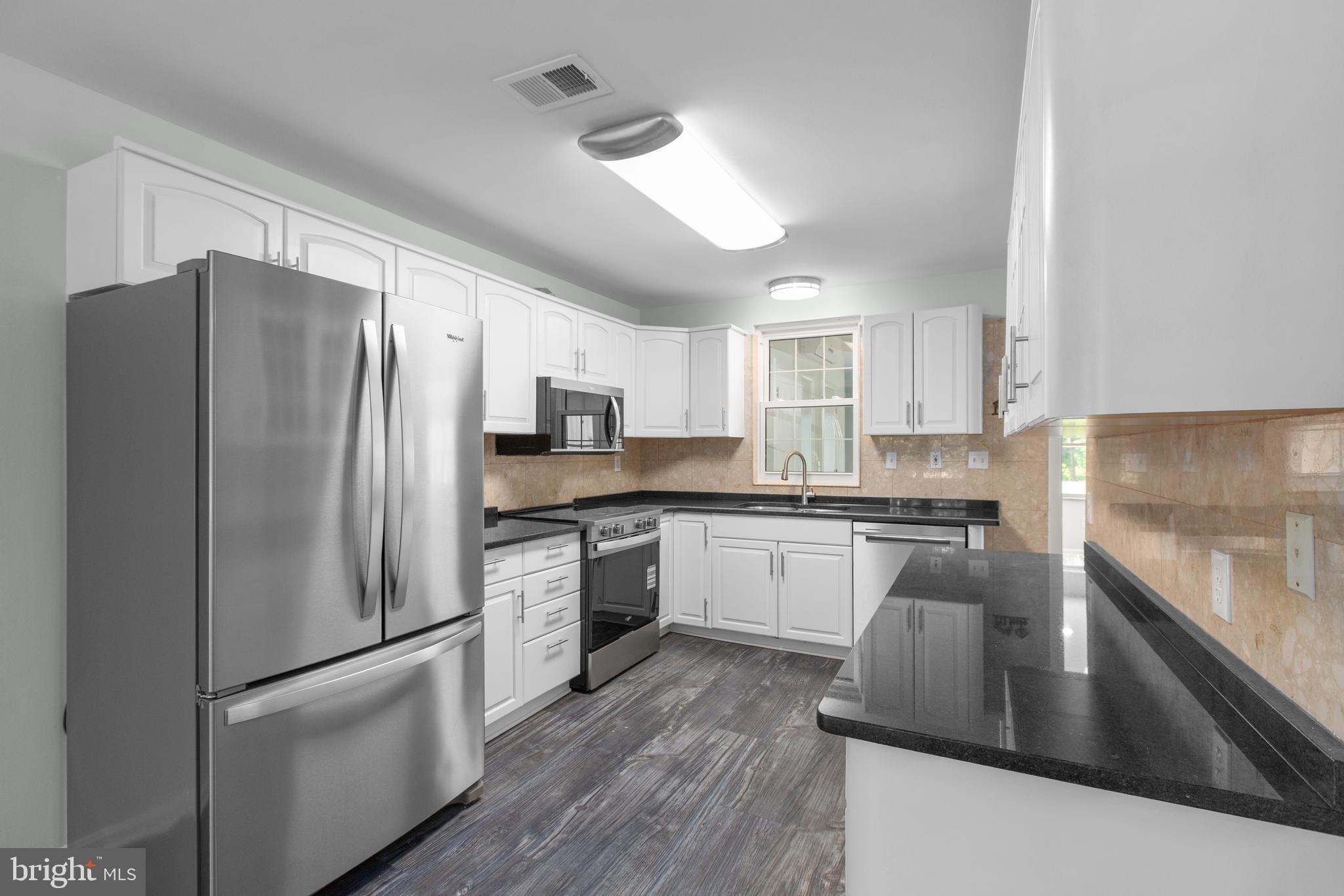 10827 Catharpin Road Spotsylvania, VA 22553 - Photo 15 of 39 a kitchen with stainless steel appliances granite countertop a refrigerator a stove a sink dishwasher a oven with white cabinets and wooden floor
