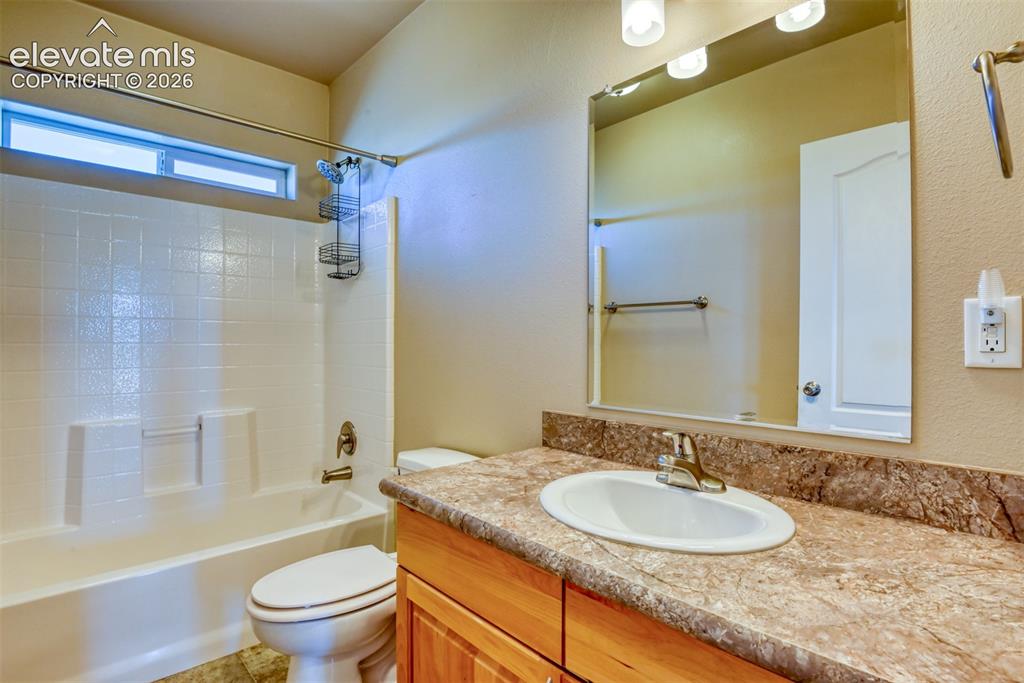 22558 Enoch Road Calhan, CO 80808 - Photo 19 of 50 a bathroom with a granite countertop sink toilet mirror and shower