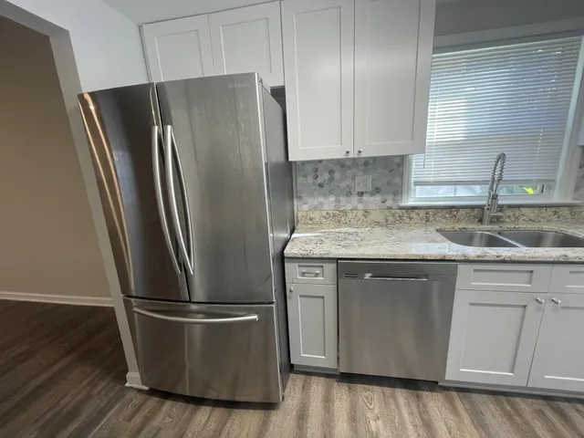a metallic refrigerator freezer sitting inside of a kitchen