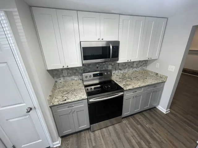 a kitchen with granite countertop a sink stove and cabinets