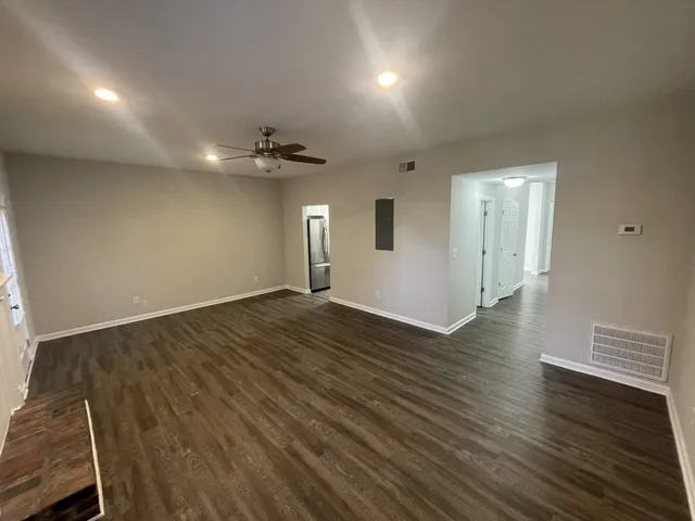an empty room with wooden floor and windows