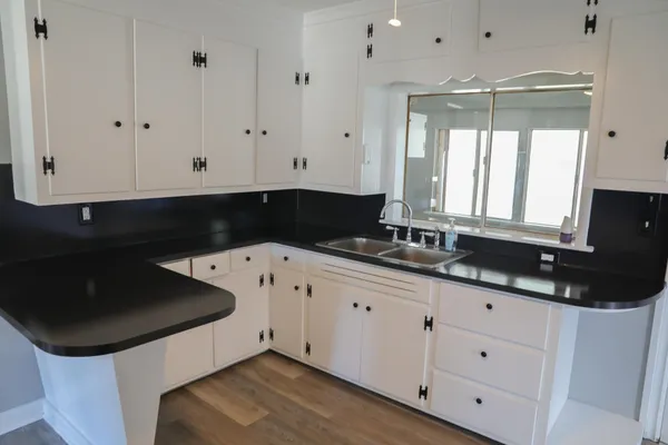 a kitchen with granite countertop white cabinets and a sink