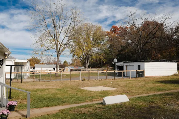 a kitchen with stainless steel appliances a stove a refrigerator a sink and white cabinets with wooden floor