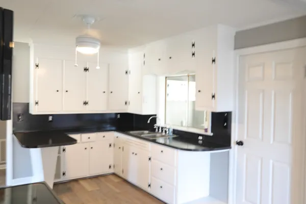 a view of kitchen with granite countertop white cabinets and black appliances