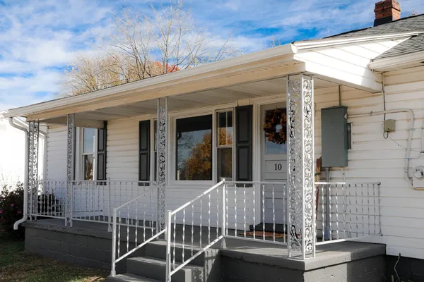 a view of a white house with a yard and covered with wooden fence