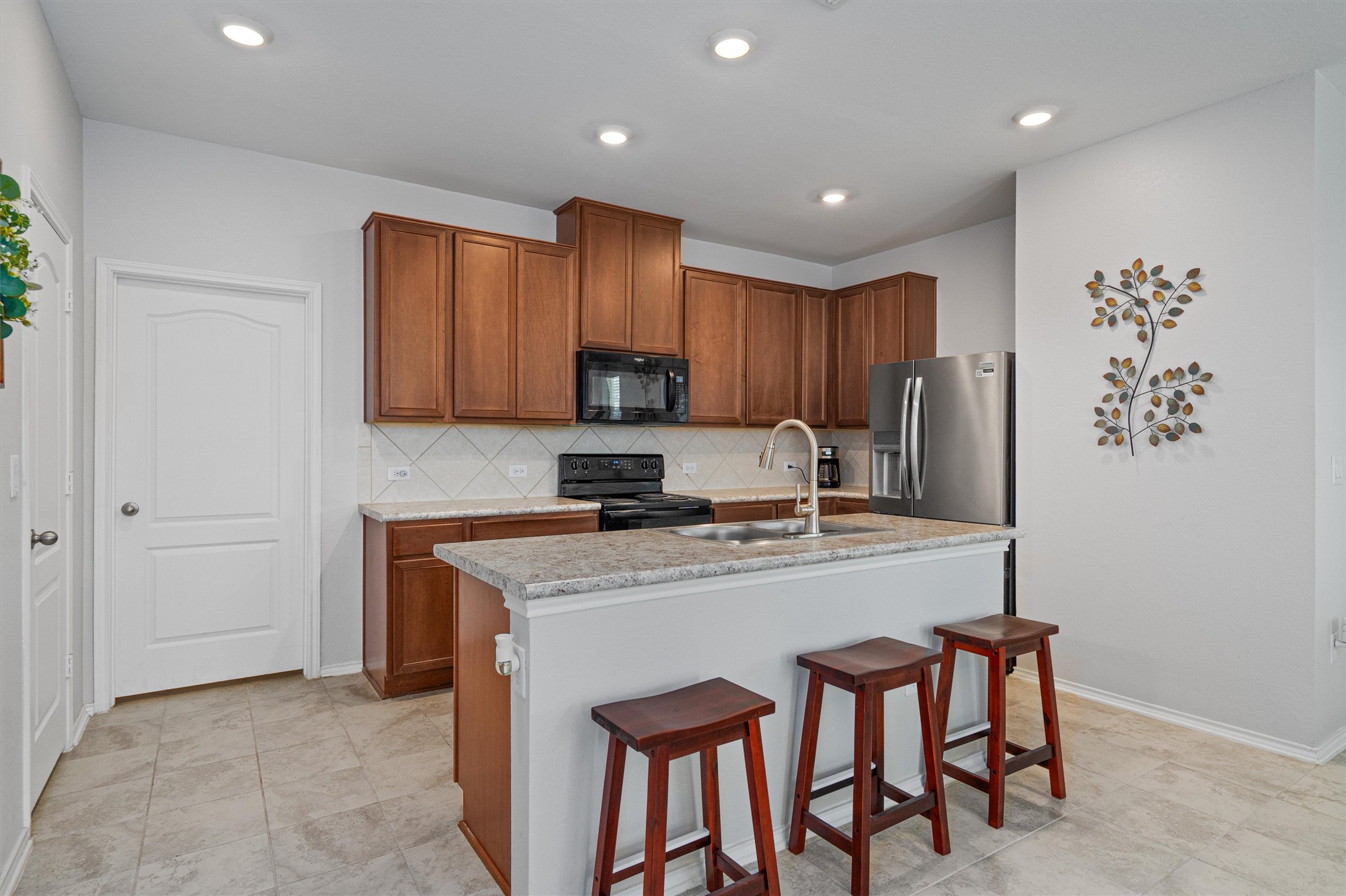 1906 Dragonfly Loop Bastrop, TX 78602 - Photo 13 of 34 a kitchen with stainless steel appliances granite countertop a refrigerator a sink a stove a dining table and chairs