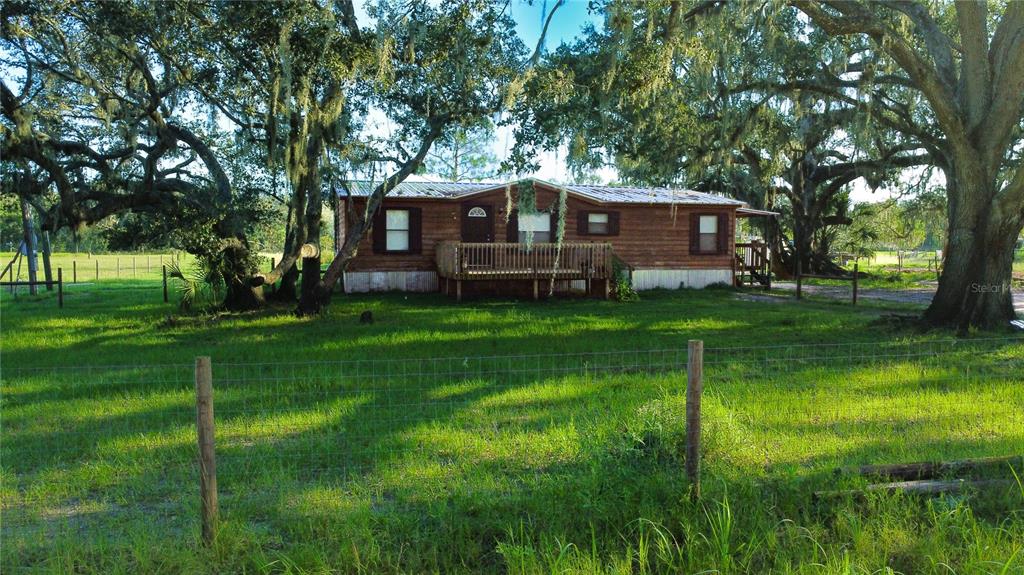 a backyard of a house with table and chairs and a large tree