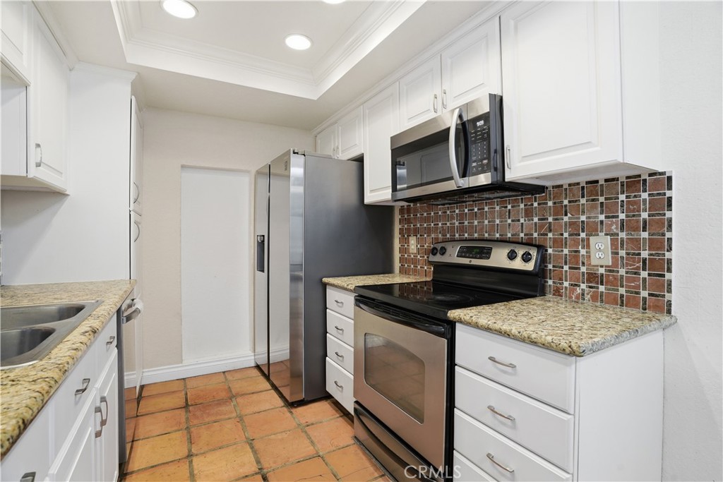 20702 El Toro Road, Unit 231 Lake Forest, CA 92630 - Photo 24 of 36 a kitchen with granite countertop a stove sink and microwave