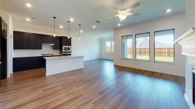 a view of an empty room with a kitchen and a window