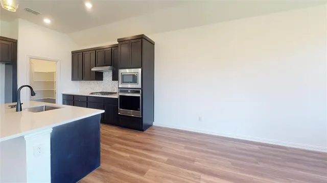 a kitchen with stainless steel appliances granite countertop a sink stove and refrigerator