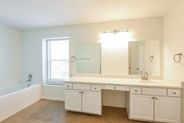 a bath room with a sink vanity and bathtub