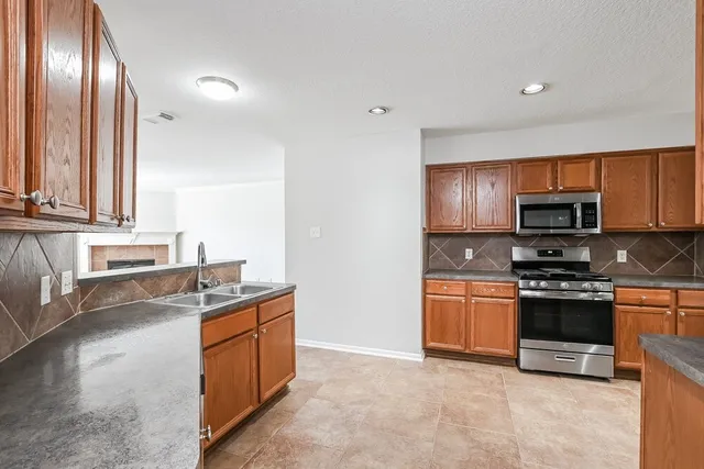 a kitchen with stainless steel appliances granite countertop a stove a sink and a microwave