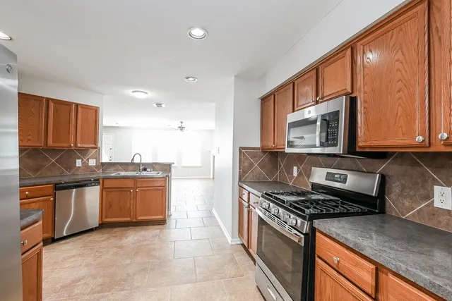 a kitchen with stainless steel appliances granite countertop a stove a sink and a microwave