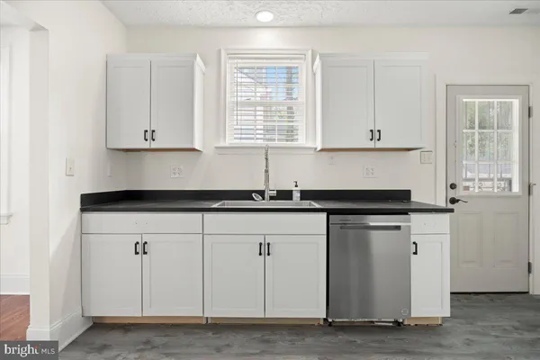 a kitchen with granite countertop white cabinets and a sink