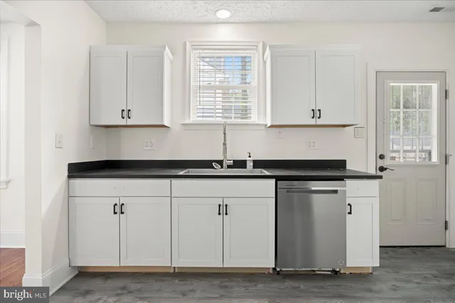 a kitchen with granite countertop white cabinets and a sink