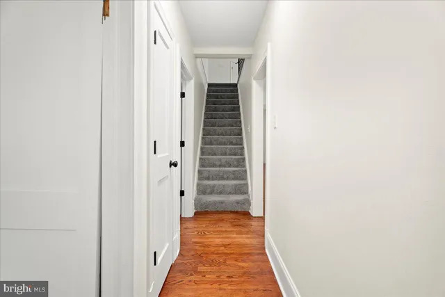 a view of a hallway with wooden floor and a bathroom