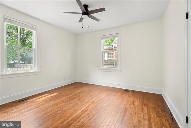 a view of empty room with wooden floor and fan