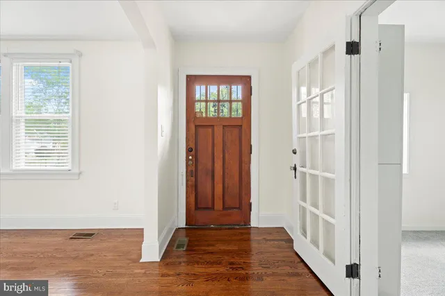 a view of a hallway with wooden floor and windows