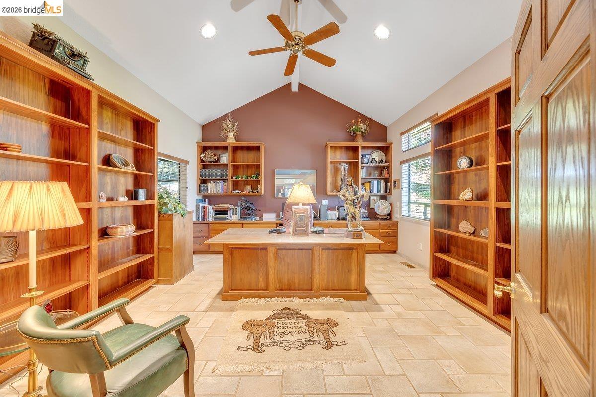 13700 Clements Road Groveland, CA 95321 - Photo 23 of 93 Vaulted ceiling with an overhead fan, extensive built-in wooden shelving, integrated wooden desk and cabinetry, transom windows, and light-toned tile flooring
