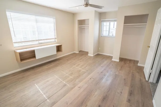 a view of an empty room with a window and wooden floor