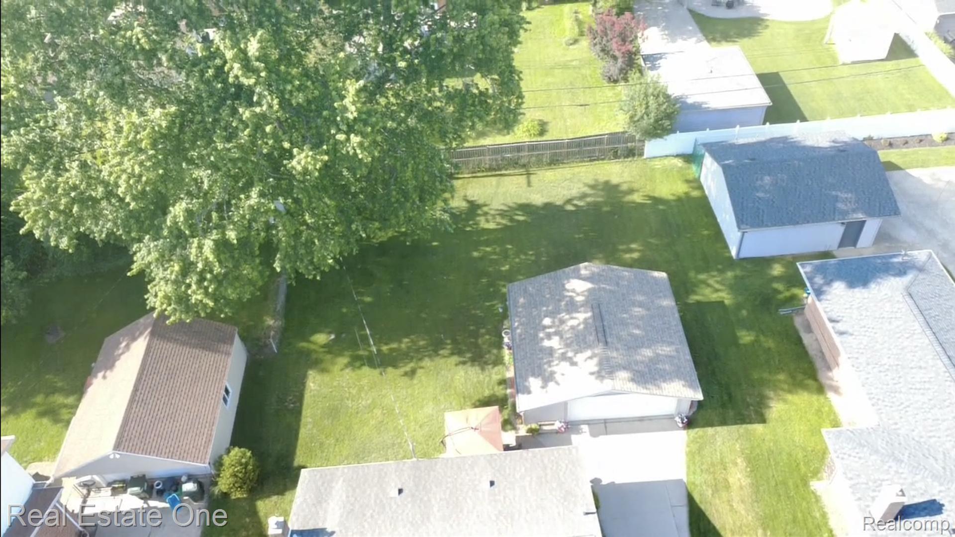 220 Winry Drive Rochester, MI 48307 - Photo 32 of 35 Expansive green lawn with mature shade trees, showcasing a detached garage with a light-colored roof and an additional outbuilding