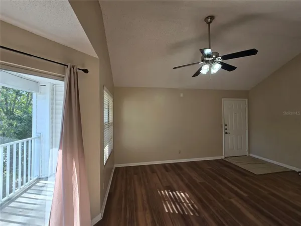 a view of empty room with wooden floor and fan