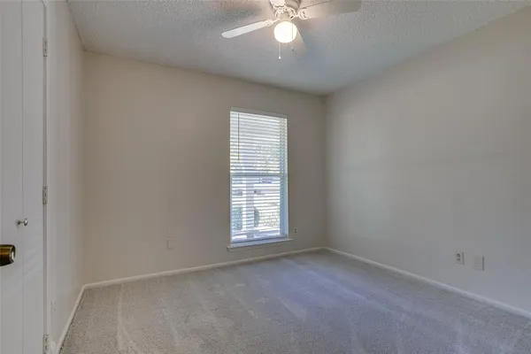 an empty room with a window and a fan