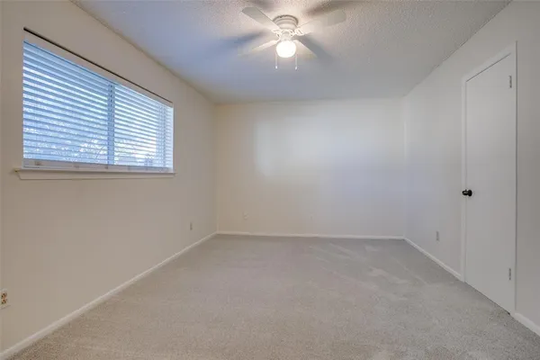 an empty room with a window and a fan