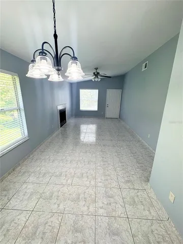 a view of an empty room with a window and chandelier fan