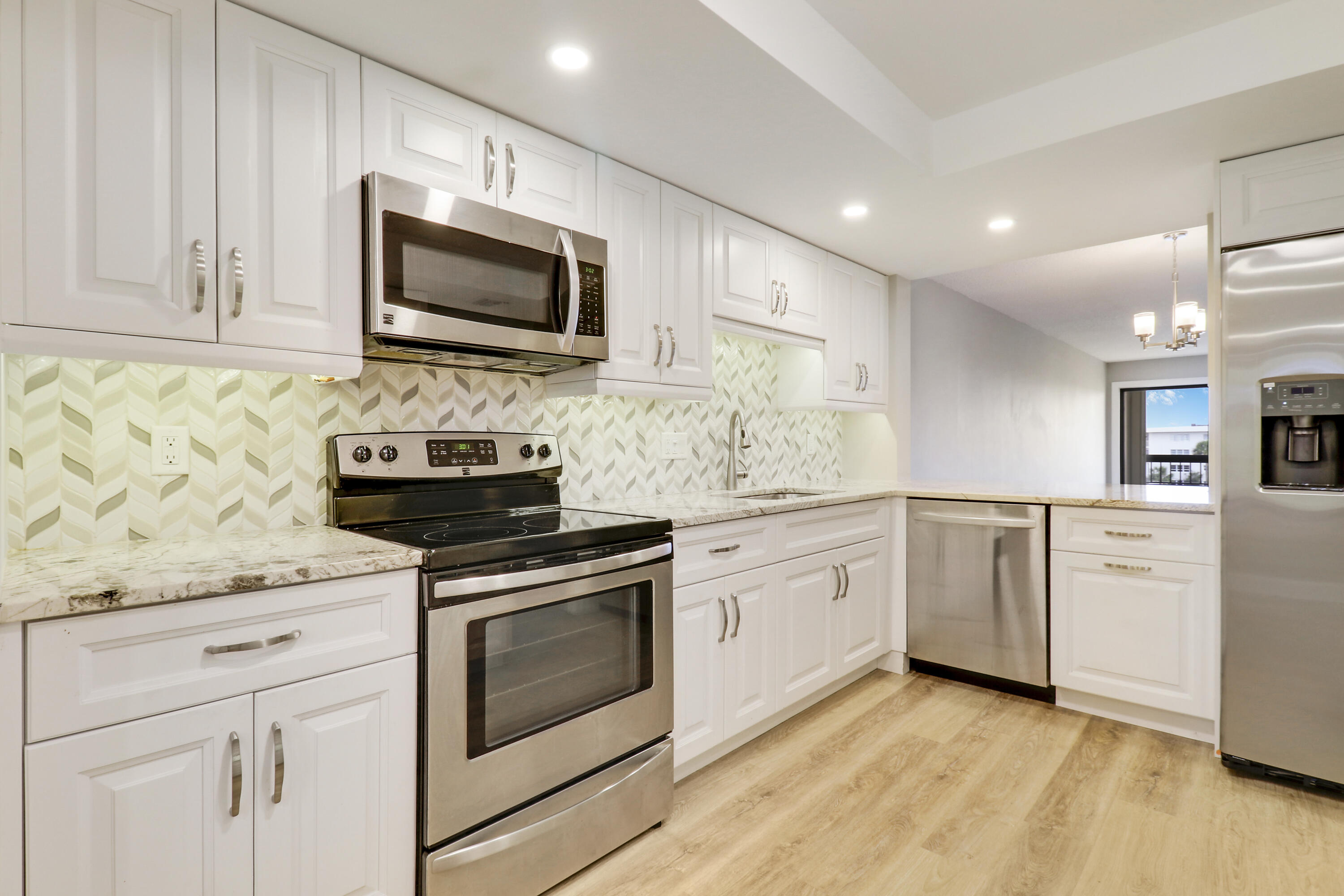 1036 Highway 1, Unit 321 North Palm Beach, FL 33408 - Photo 8 of 40 a kitchen with granite countertop white cabinets stainless steel appliances and sink