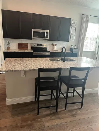a kitchen with stainless steel appliances a stove a sink a microwave a refrigerator and cabinets