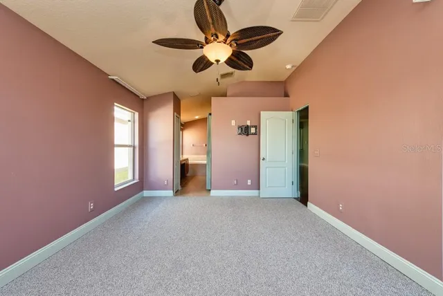 en empty room with windows and ceiling fan