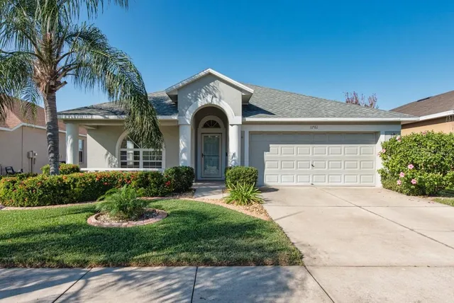 a front view of a house with a yard and potted plants