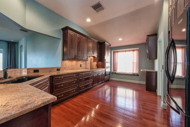 a kitchen with sink refrigerator and wooden floor