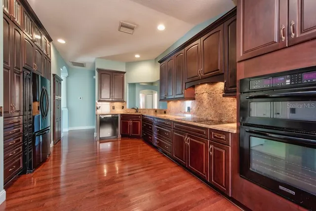 a large kitchen with stainless steel appliances wooden floors and wooden cabinets