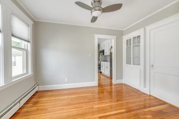 a view of empty room with wooden floor and fan