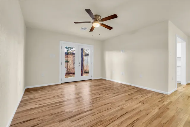 a view of an empty room with window and wooden floor