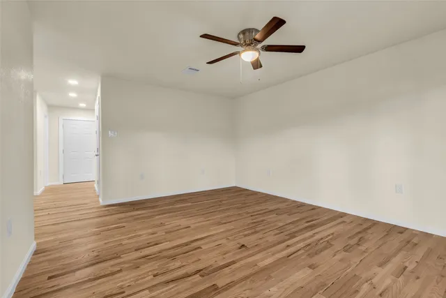 an empty room with wooden floor and a ceiling fan