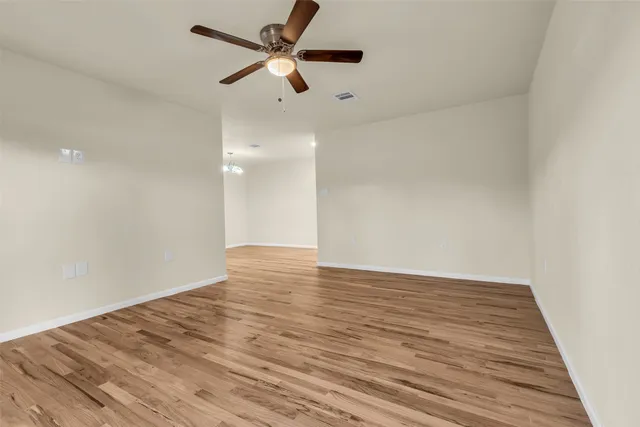 an empty room with wooden floor and a ceiling fan