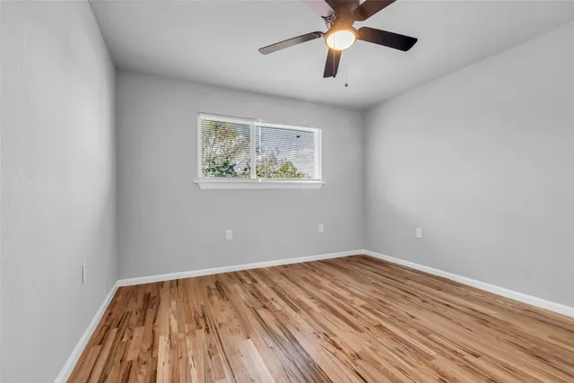 an empty room with a window and a ceiling fan